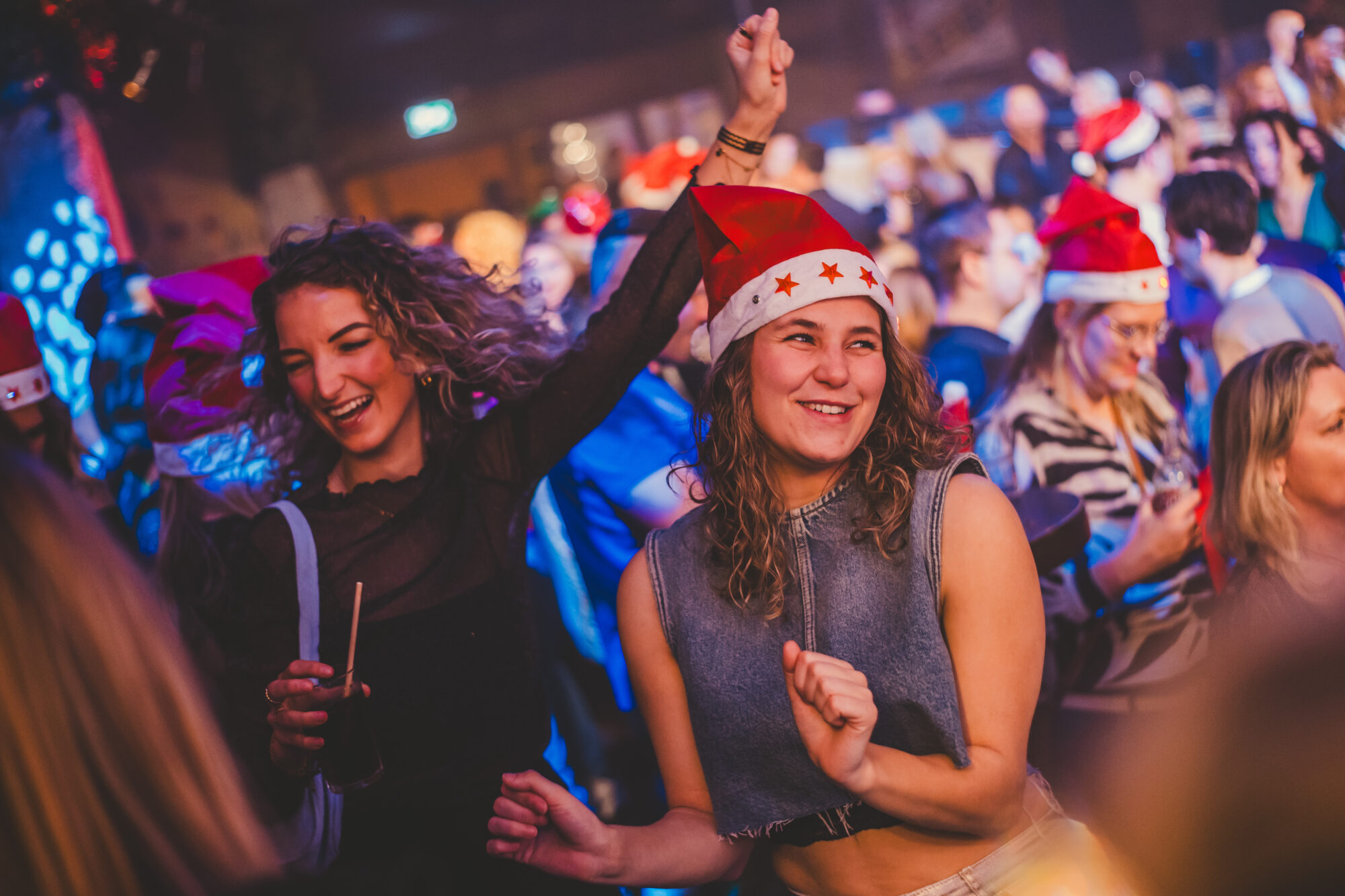 Twee vriendinnen met kerstmutsen dansen lachend op het 90s kerstfeest in Lucky Rijssen