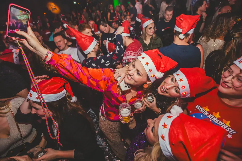 Vriendengroep met kerstmutsen maakt een selfie tijdens het kerstfeest in Lucky Rijssen