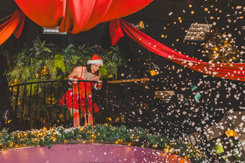 Kerstelf op het balkon boven een sneeuwbui van confetti in Lucky Rijssen